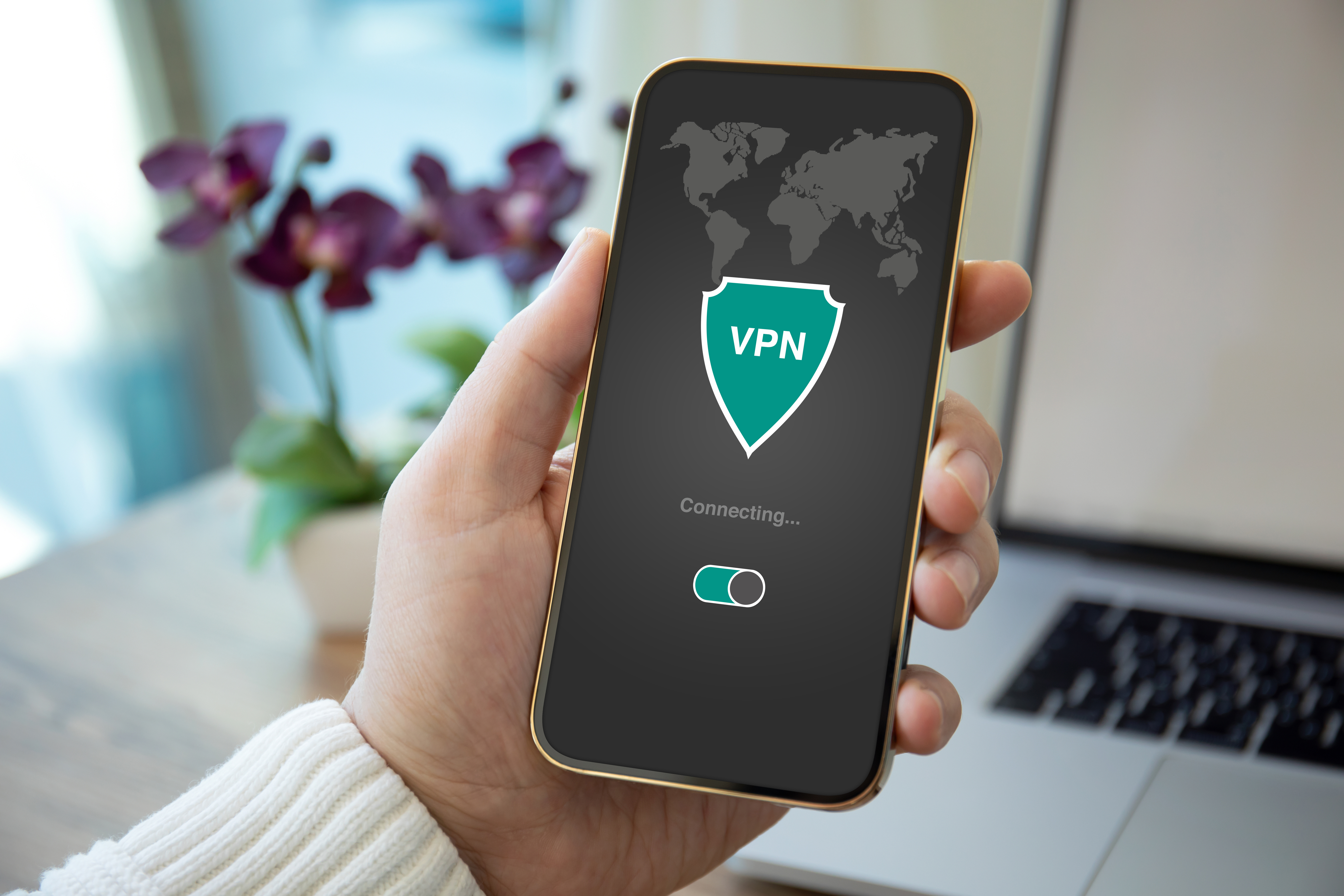 Hand holding a smartphone displaying a VPN app connecting screen with world map