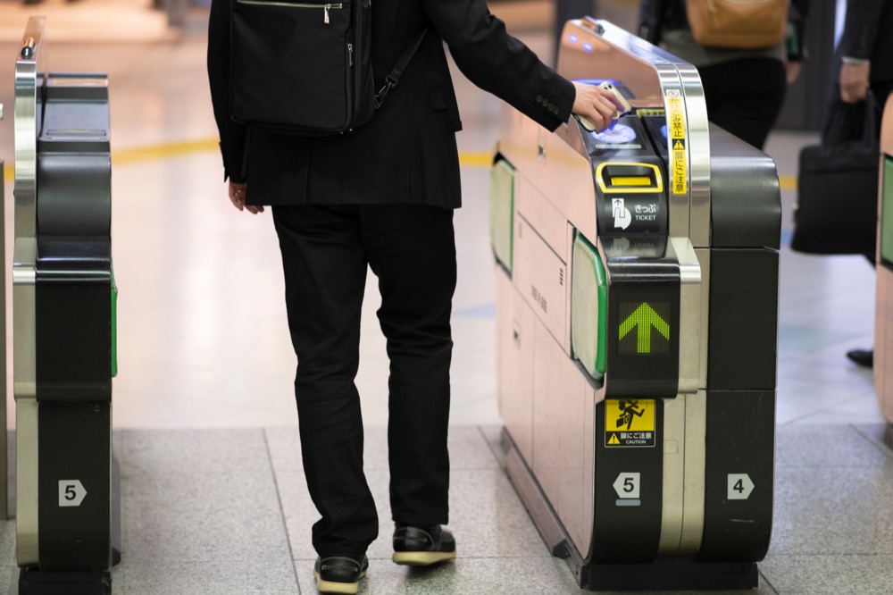 A person tapping a smartphone to pass through a Japanese train station ticket gate