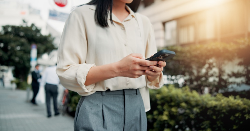A woman using phone while she walk on a street