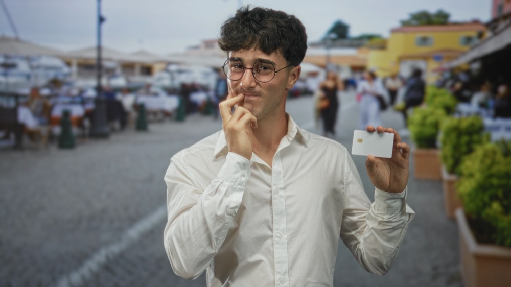 A thoughtful man holding a card while considering how to set up Mobile Suica for Japan travel